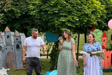 Dzieci siedzą na kocach, przed nimi dwie kobiety i mężczyzna - aktorzy spektaklu.