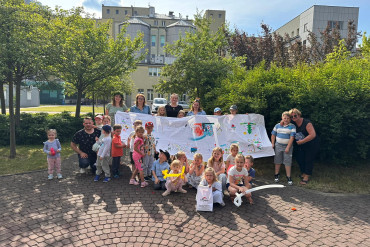 Dzieci oraz dorośli trzymają wielki rysunek
