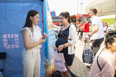 Pani Położna stoi naprzeciwko Pani w widocznej ciąży, rozmawiają ze sobą.