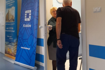 Panie pielęgniarka trzyma uchylone drzwi, pacjent wchodzi do gabinetu.