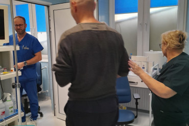Pielęgniarka prowadzi pacjenta. W drzwiach stoi lekarz, czekając na pacjenta