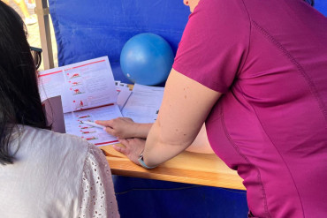 Fizjoterapeutka pokazuje ćwiczenia na kartce papieru siedzącej na krześle kobiecie.